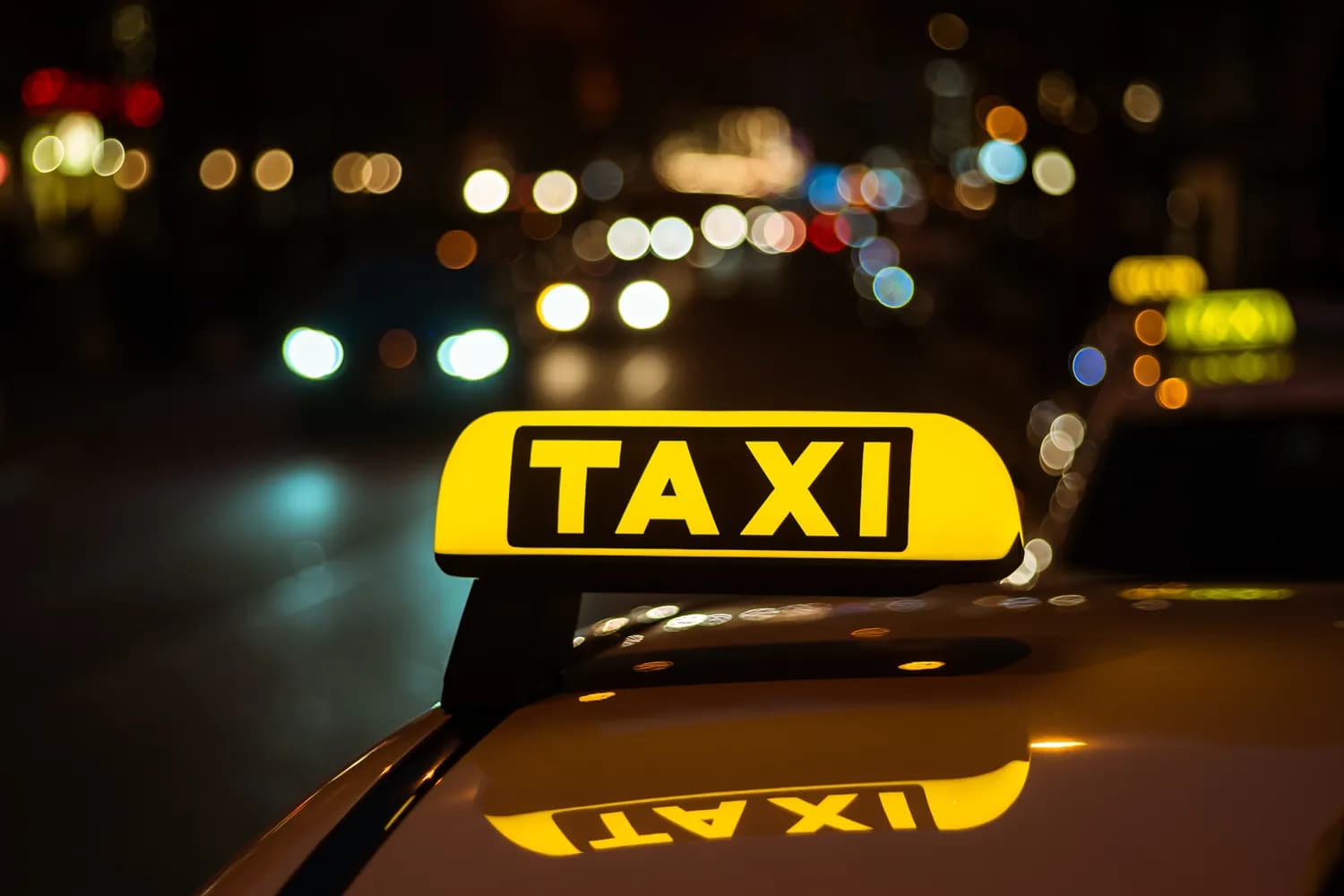 Taxi oznaka na krovu sa noćnim gradskim svetlima